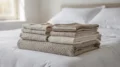 Bettwäsche aus Baumwolle, Leinen, Wolle und Seide in neutralen Farben auf einem Bett